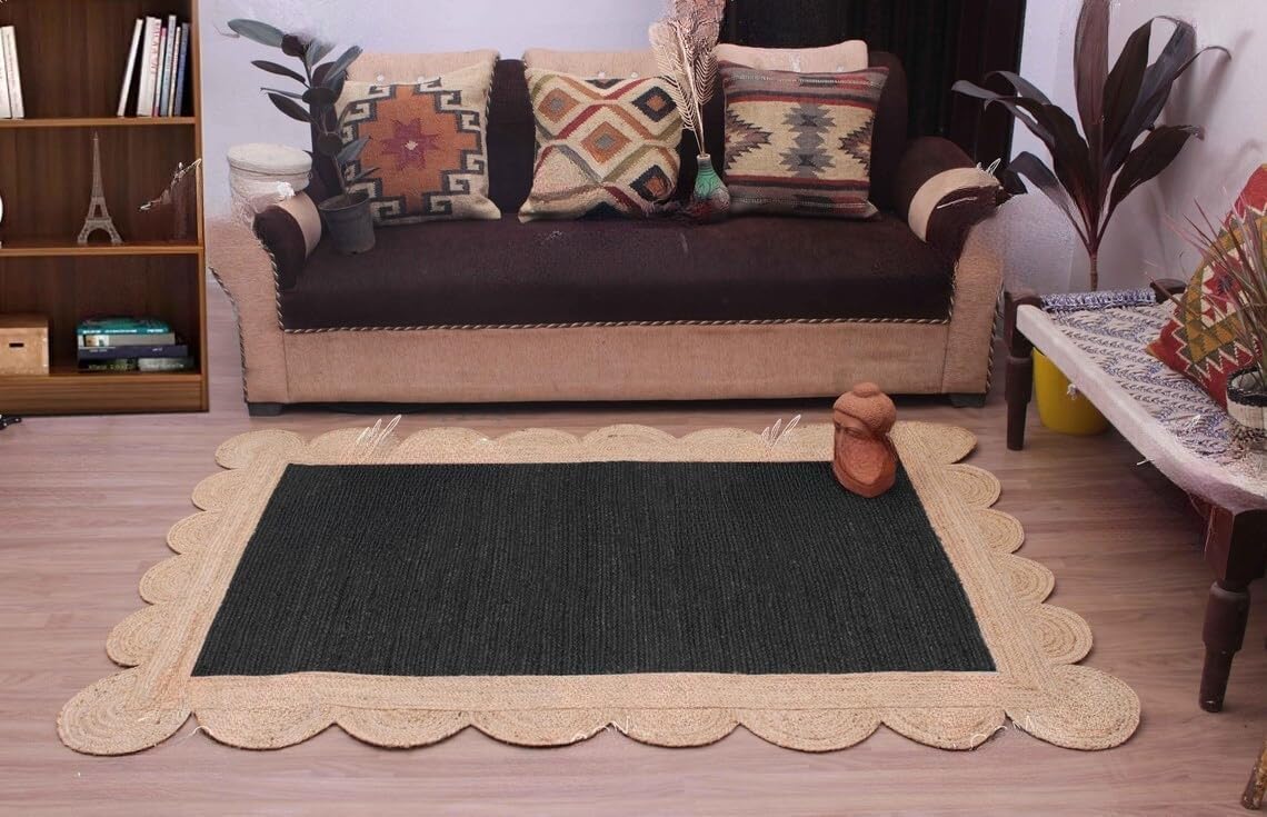 A rectangular area rug with a dark charcoal center and a natural beige scalloped jute border, styled in a living room setting in front of a brown sofa.