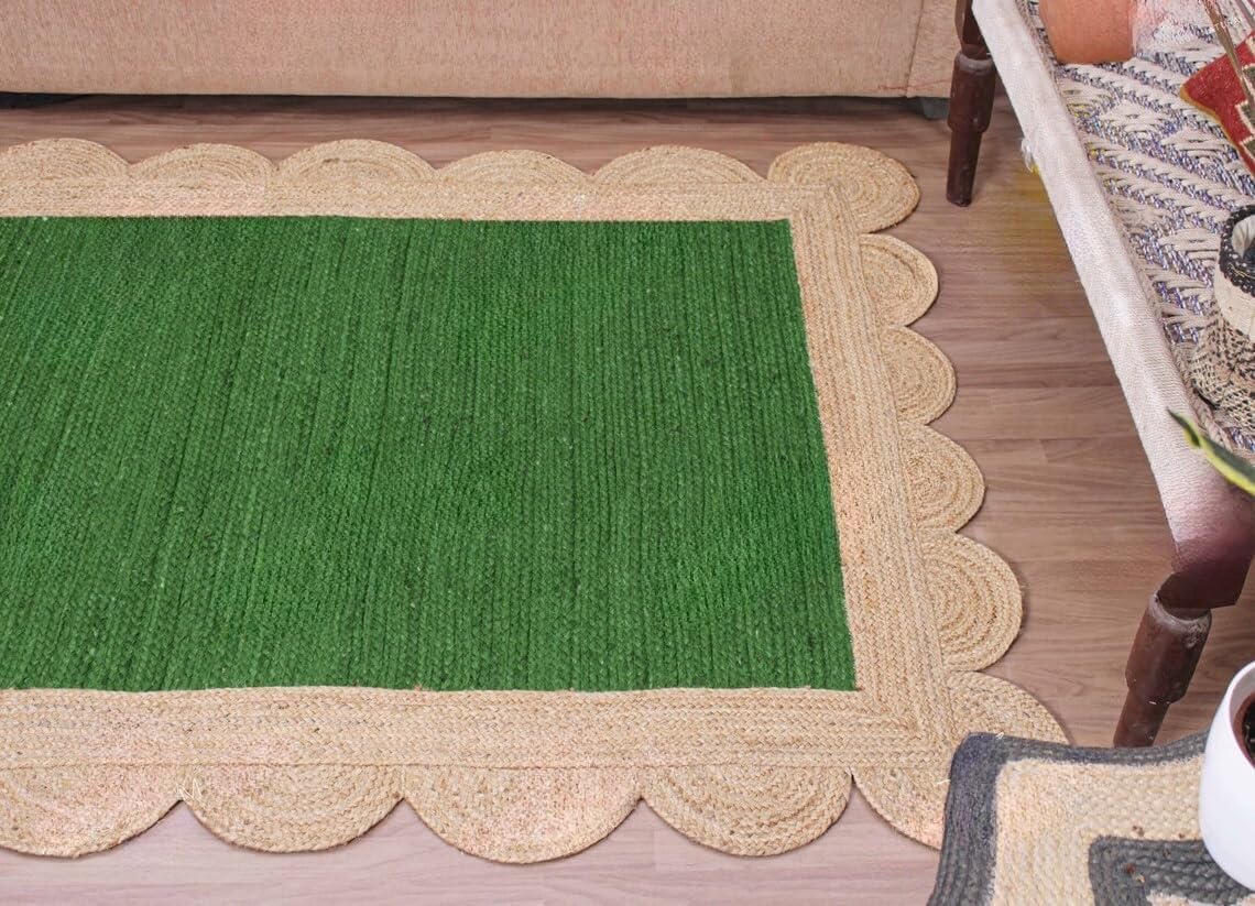 A rectangular green woven rug with a scalloped natural jute border, shown on a light wood floor in a home setting.