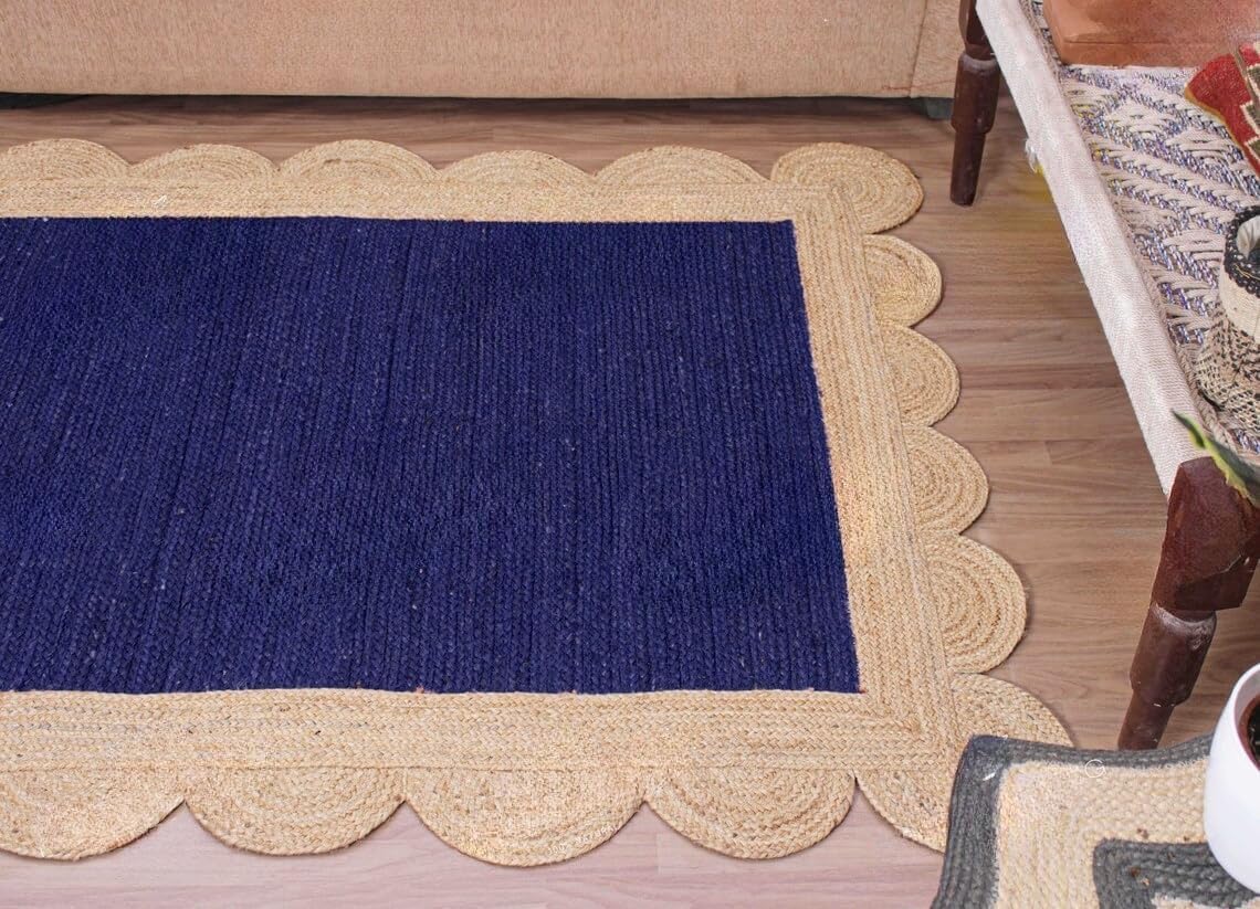 A rectangular woven rug with a deep navy blue center and a natural beige braided border, styled on a light wood floor in a home setting.