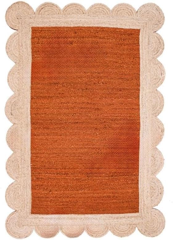 A rectangular woven rug with a warm rust-orange center and a natural beige scalloped braided border, shown flat against a white background.