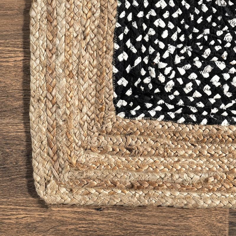 Close-up of a woven rug corner with a textured pattern on a wooden floor.