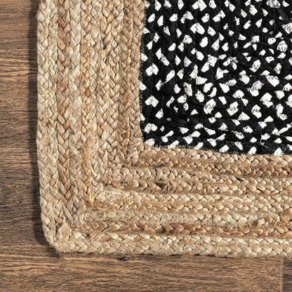 Close-up of a woven rug corner with a textured pattern on a wooden floor.