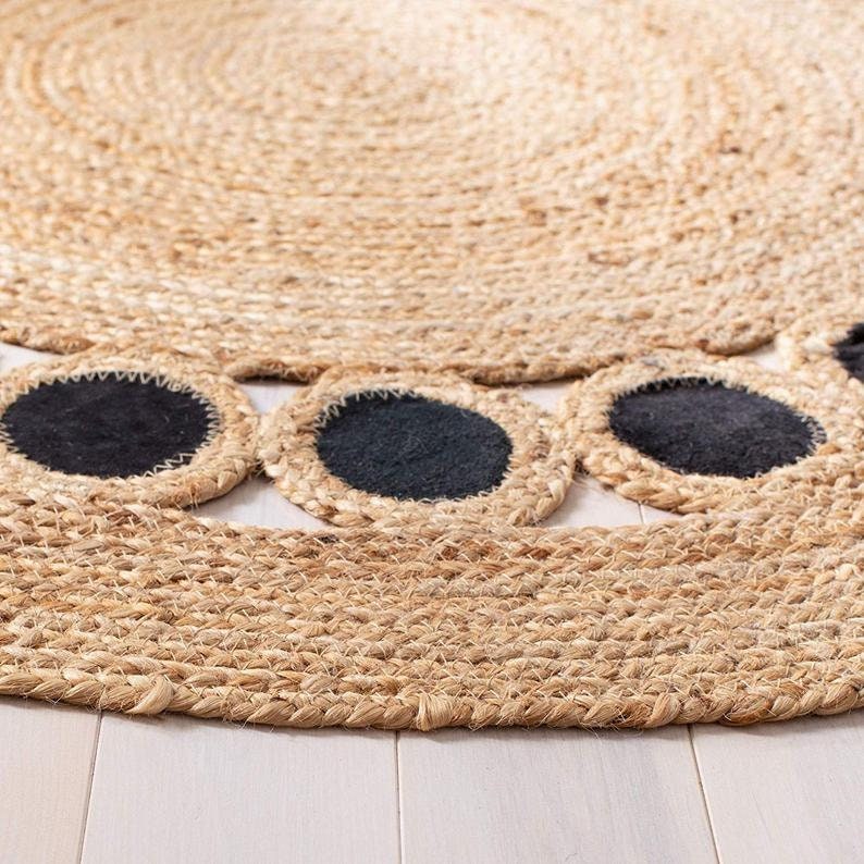 Round woven mat with black circular cutouts on a light wooden floor