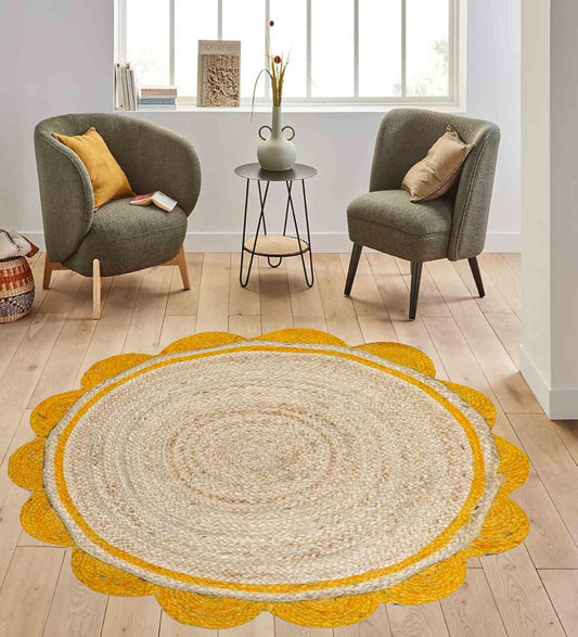 Round woven rug with yellow border on a wooden floor, flanked by two gray chairs with cushions.
