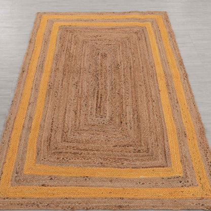 Brown braided rug with yellow border on a gray floor