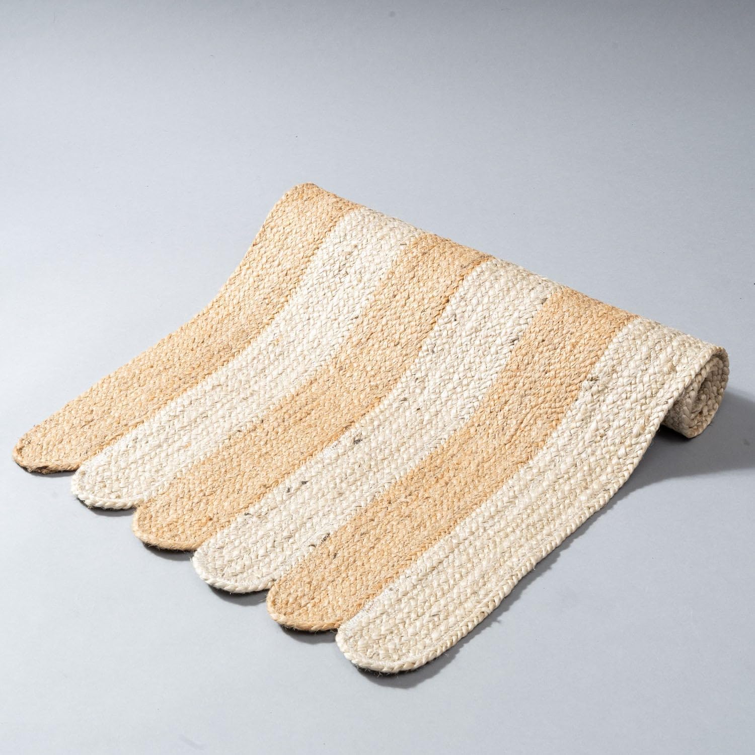 Striped bath mat with beige and white colors on a gray background