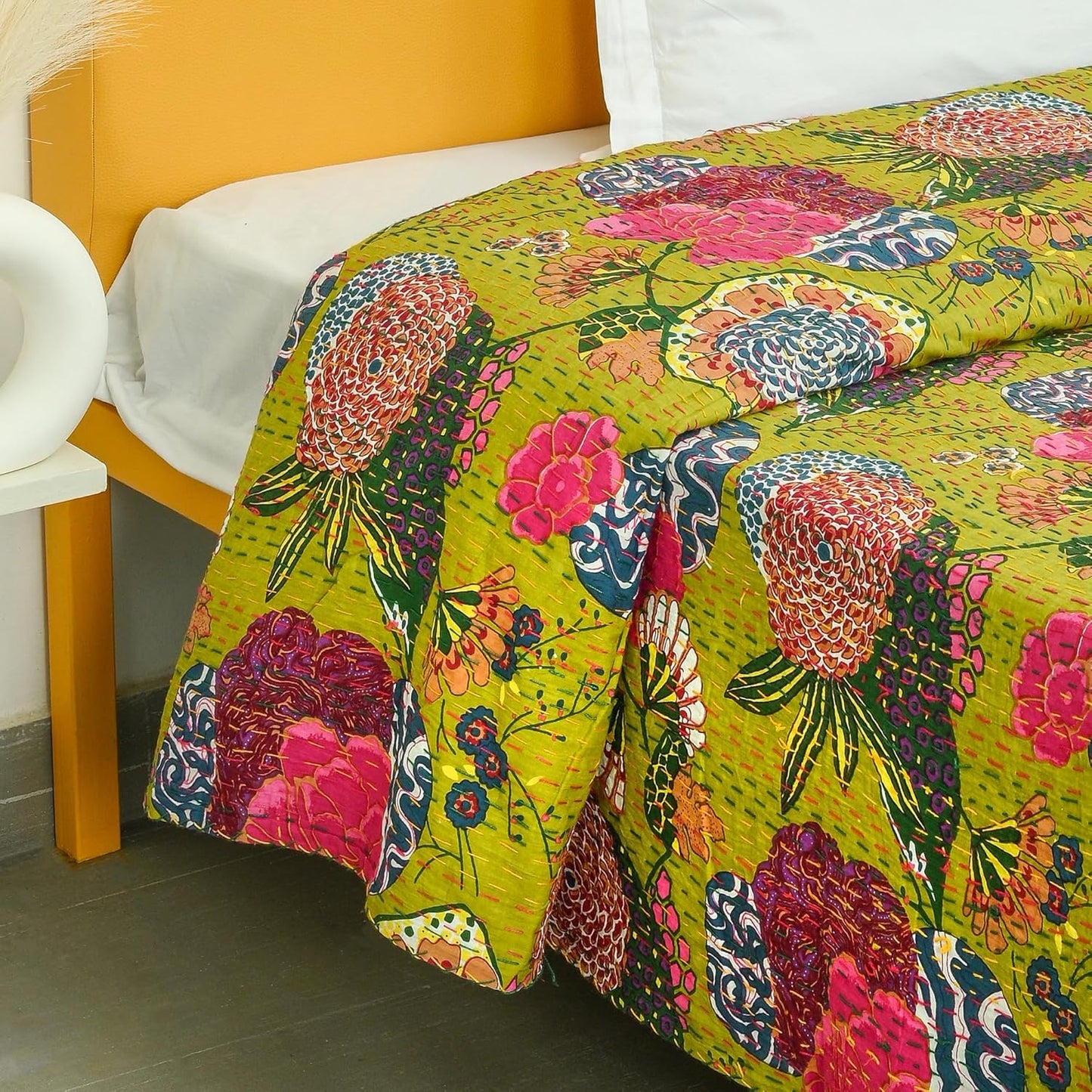 Colorful floral-patterned quilt on a bed with a yellow headboard.