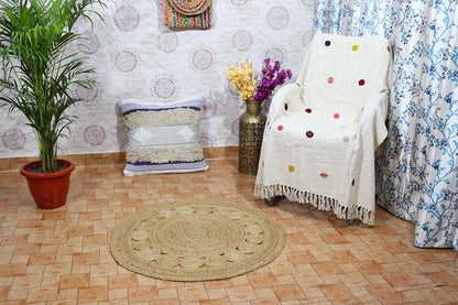 Living room with a round jute rug, chair with a polka dot blanket, and decorative elements.
