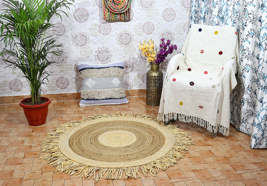 Living room with a round braided rug, white armchair with colorful polka dot blanket, and decorative pillows.