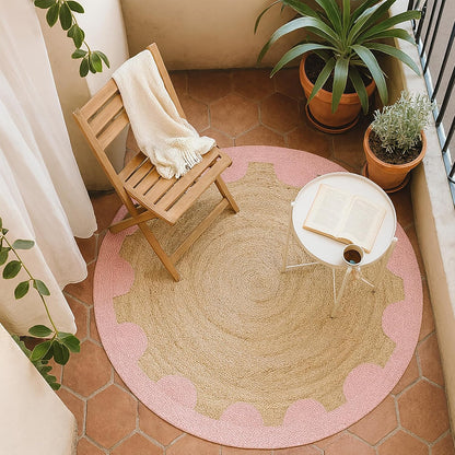 Natural Jute Area Rug in round shape with a pink scalloped edge, placed under a chair and table on a patio.