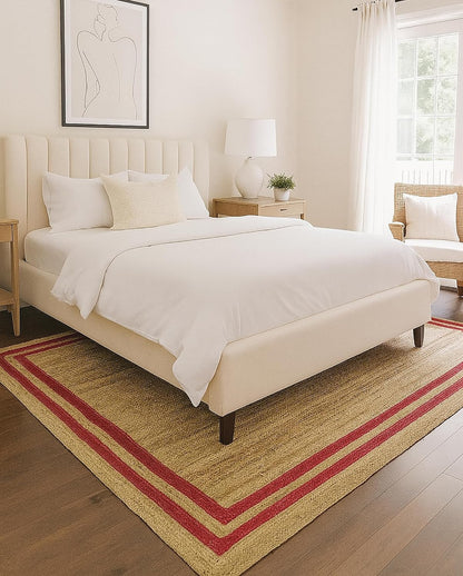 Natural Jute Area Rug with red border placed under a bed in a bright, modern bedroom setting