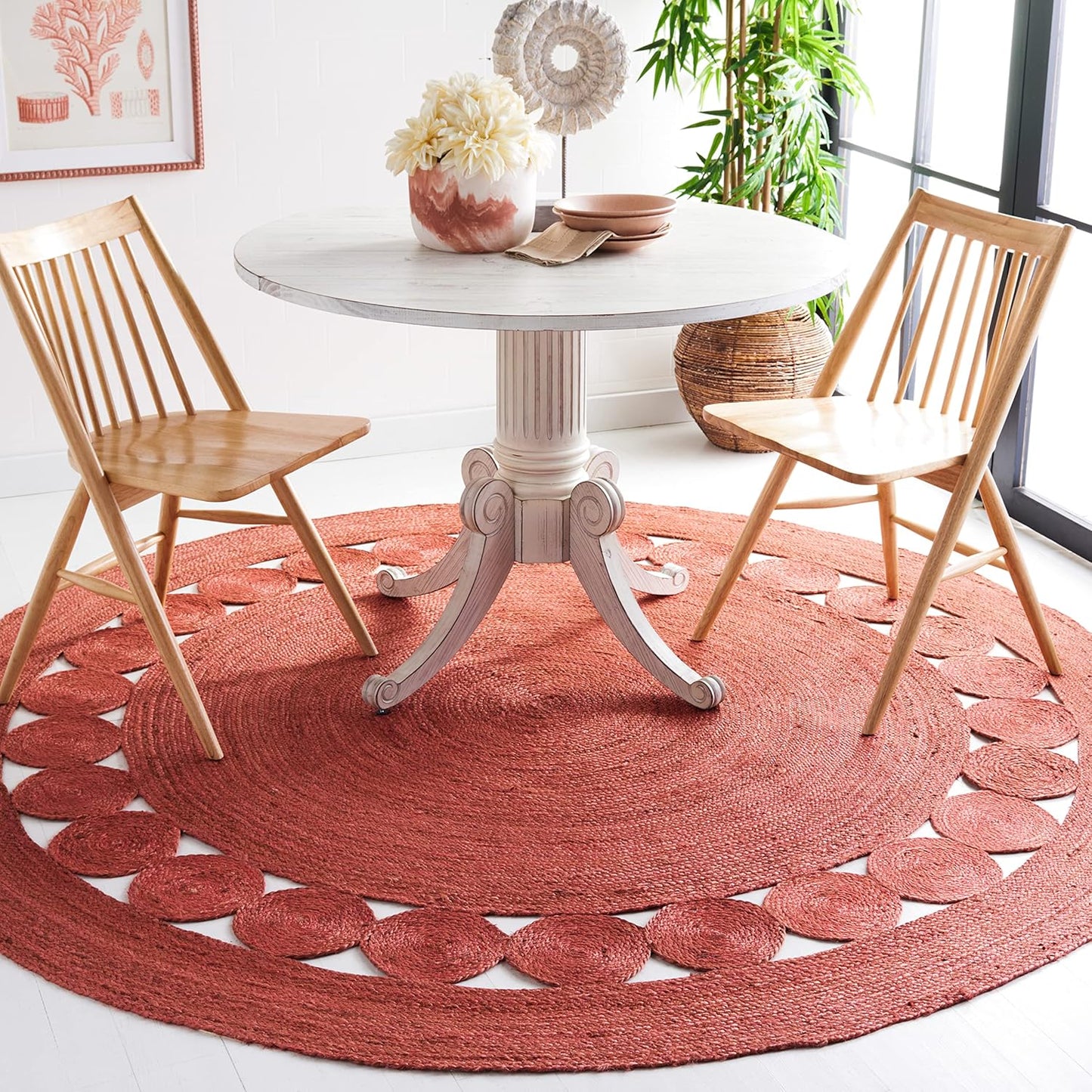 Round coral woven area rug with a decorative pattern under a wooden dining table and chairs.