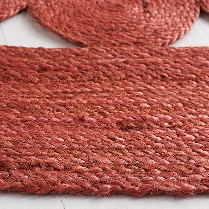 Rust-colored braided jute rug, handwoven, eco-friendly, adds texture to home decor.