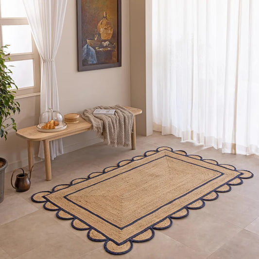 Beige rug with decorative border in a room with a wooden bench and plant
