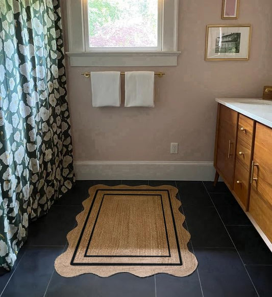 Bathroom with floral shower curtain, towel rack with towels, wooden vanity, and decorative rug.