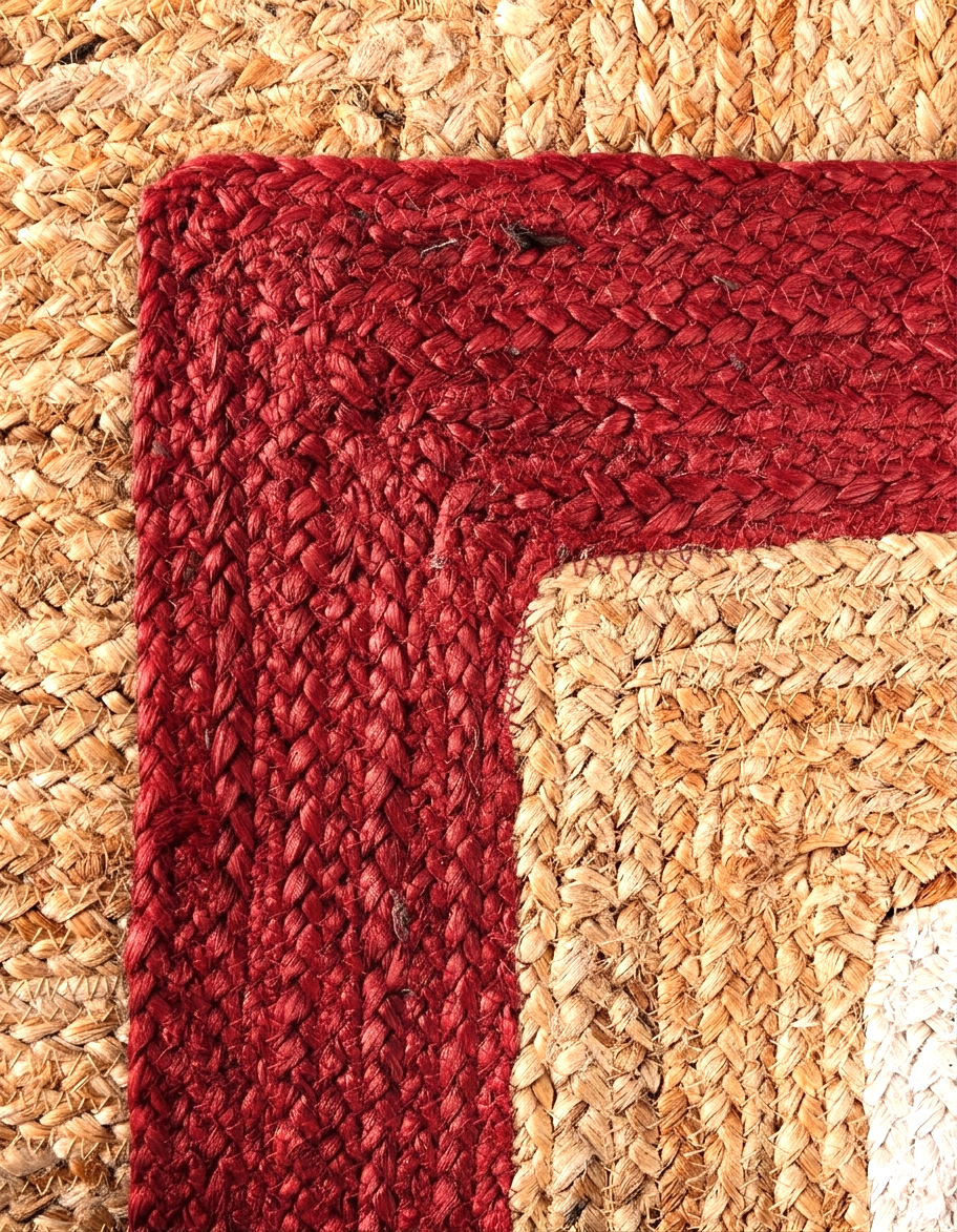 Close-up of a red braided rug corner on a beige woven surface
