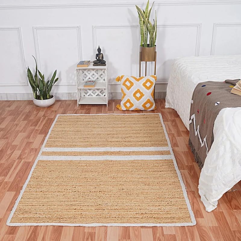 Beige rug on a wooden floor with a bed, nightstand, and plants in the background.
