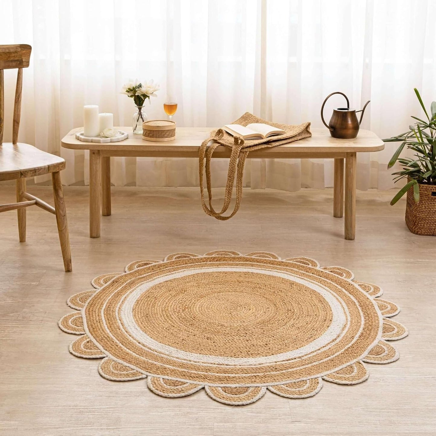A round braided jute rug with a scalloped edge, styled in a bright, modern room on a light wood floor in front of a low wooden table.