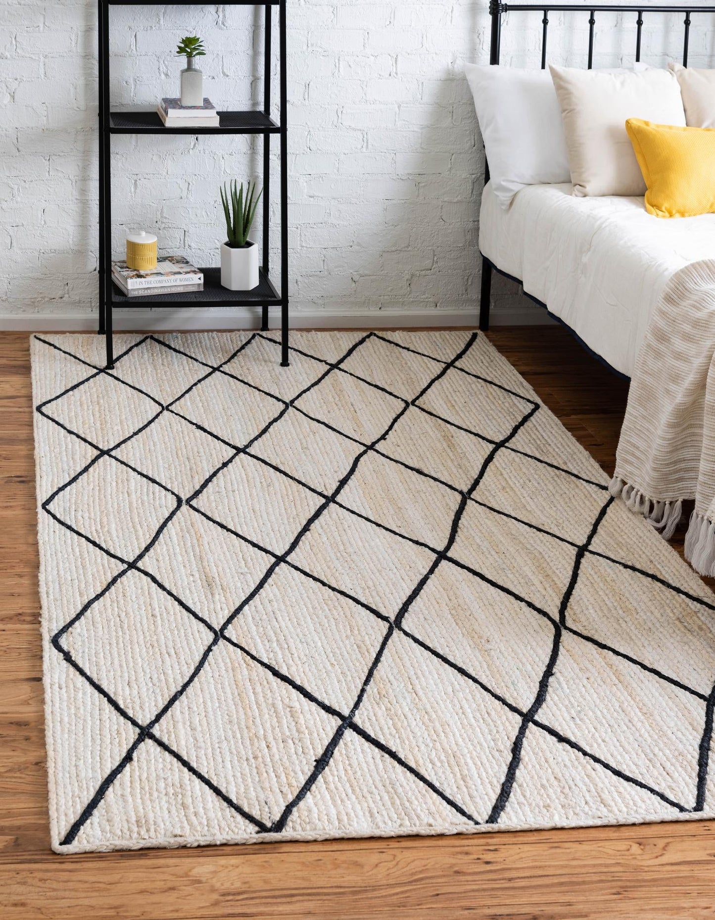 Beige area rug with black geometric pattern in a bedroom setting