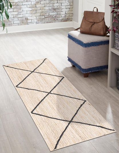 Beige runner rug with black geometric patterns on a wooden floor, next to a gray ottoman with a brown backpack.