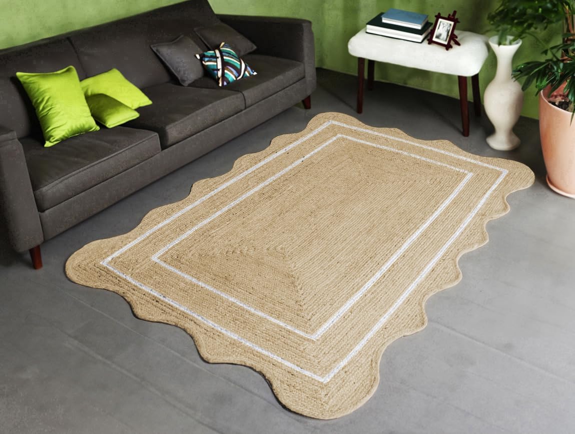 Beige rug with scalloped edge on a gray floor, with a gray sofa and green wall in the background.
