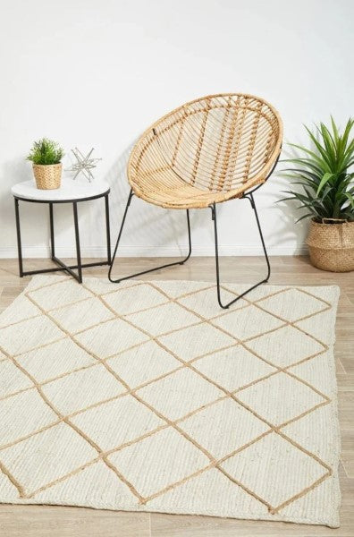 Wicker chair on a patterned rug with a side table and plants in a room.