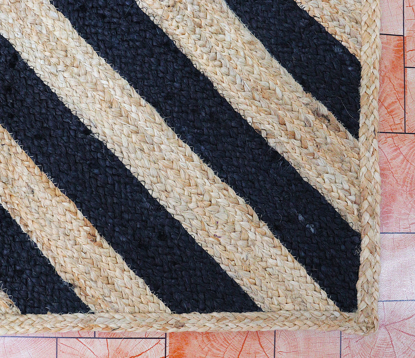 Woven mat with black and beige stripes on a wooden floor.