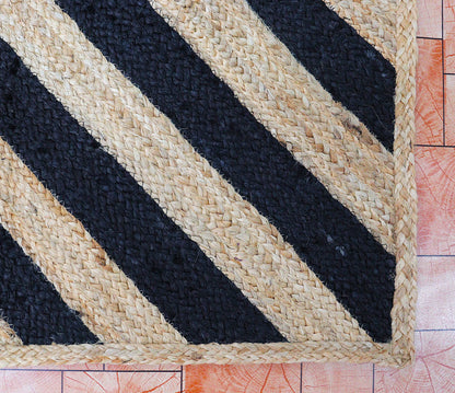 Woven mat with black and beige stripes on a wooden floor.