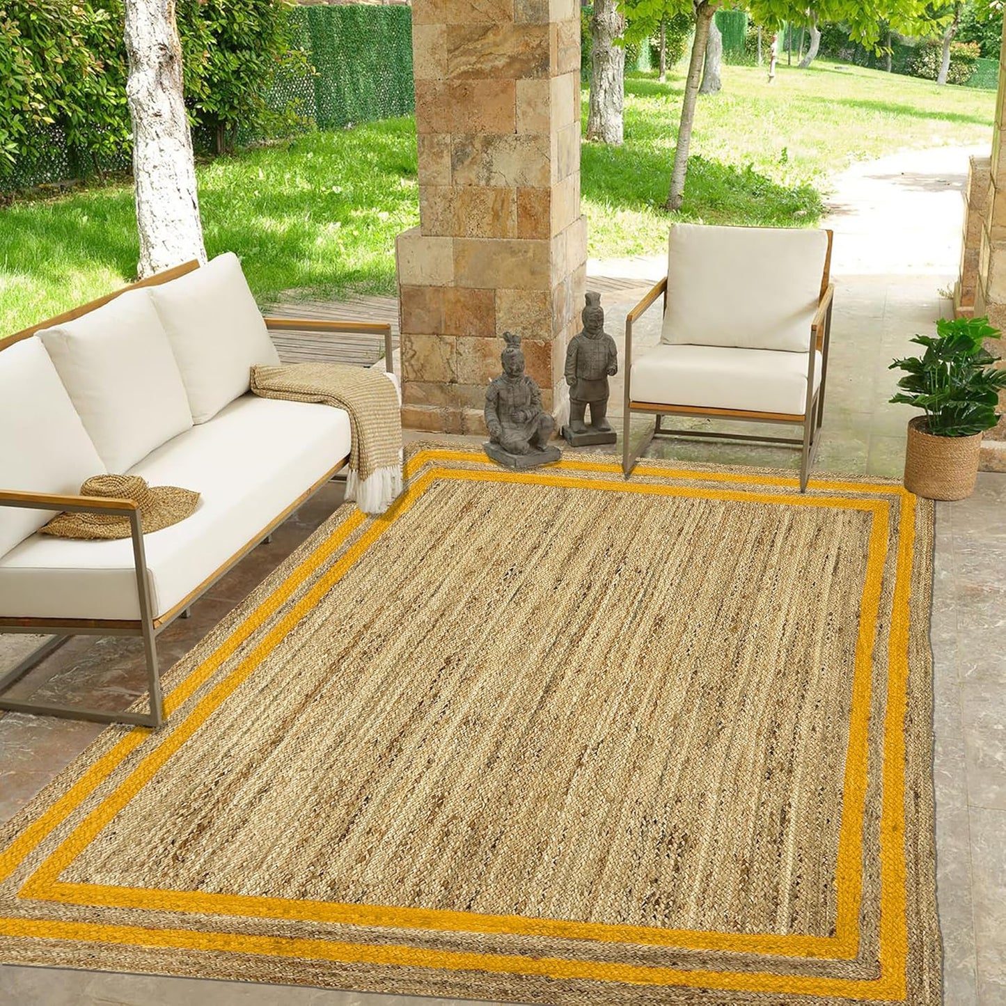 Outdoor patio with a beige rug, white chairs, and a stone wall.