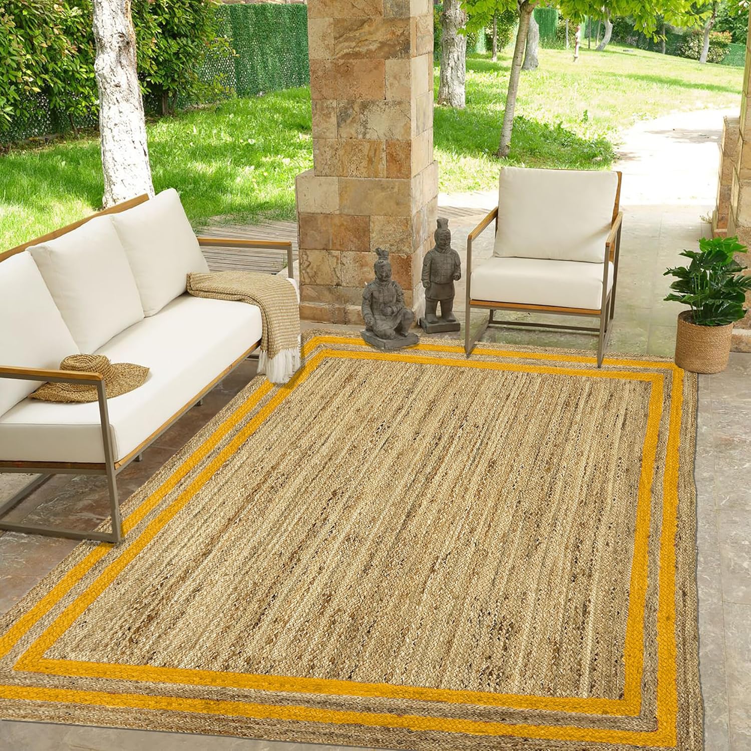 Outdoor patio with a beige rug, white chairs, and a stone wall.