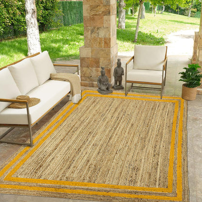 Outdoor patio with a beige rug, white chairs, and a stone wall.
