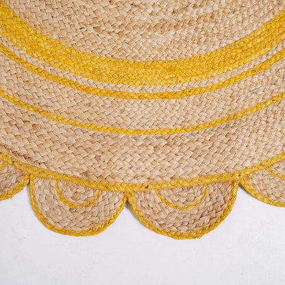 Close-up of a woven natural fiber rug or mat with bright yellow braided stripes and scalloped edges on a white background.