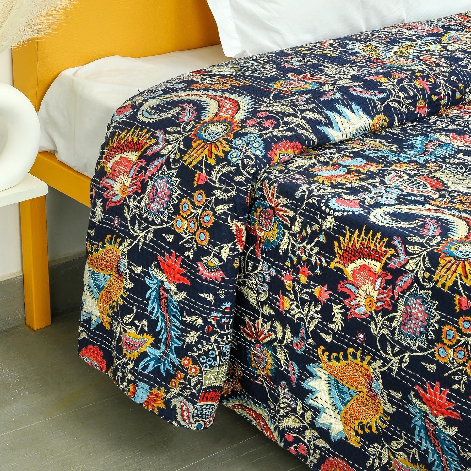 Colorful floral-patterned quilt on a bed with a yellow headboard.