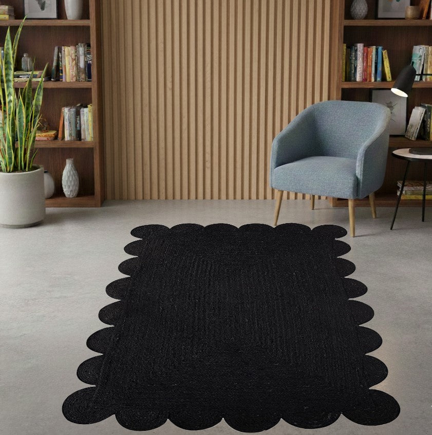 Black scalloped rug in a room with a blue chair and bookshelves.