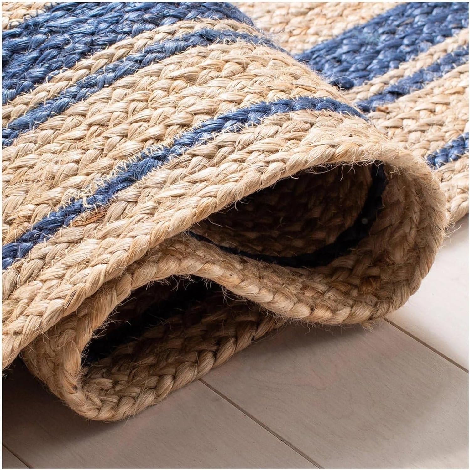 Rolled-up jute rug with blue stripes on a light-colored floor.