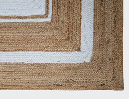 Close-up of a woven jute rug with a white border on a plain background
