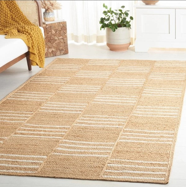Beige area rug with geometric pattern in a room with a chair and plant.