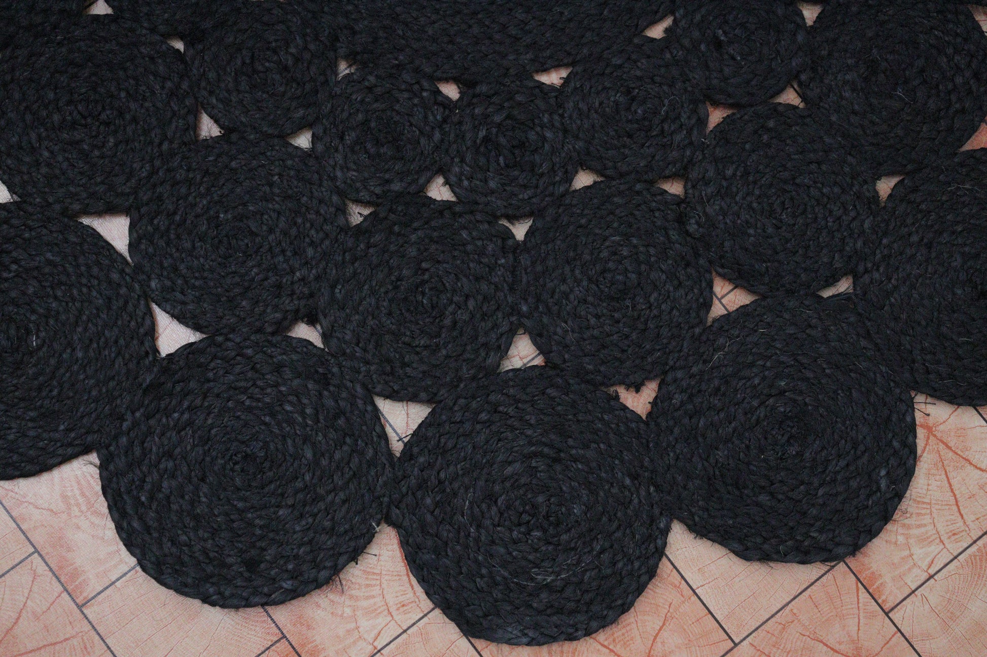 Black circular coasters arranged on a tiled floor