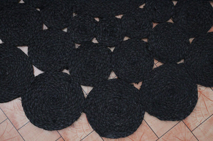 Black circular coasters arranged on a tiled floor