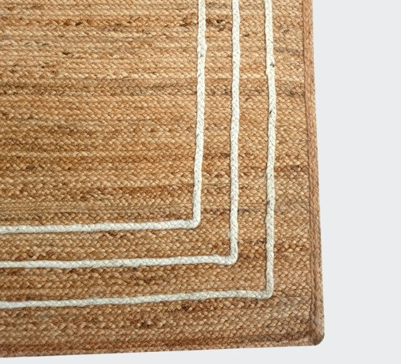 Close-up of a woven rug with a striped border on a light gray background