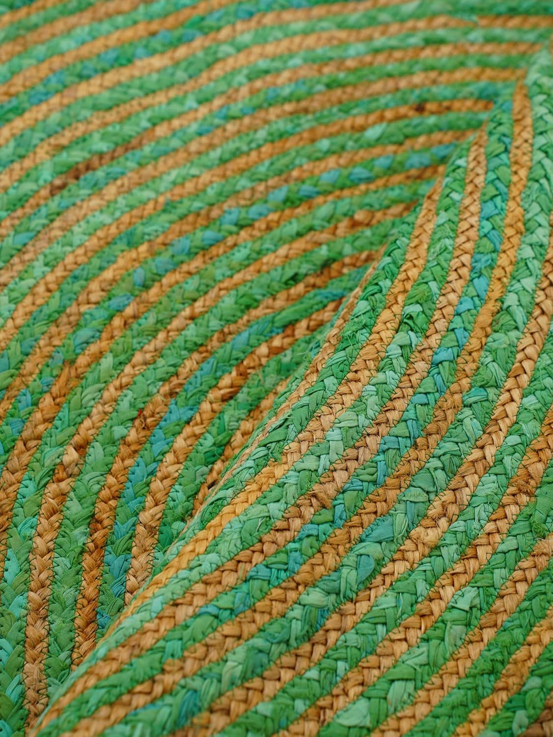 Handwoven straw mat in green and gold with a spiral pattern, ideal for home decor or outdoor use.