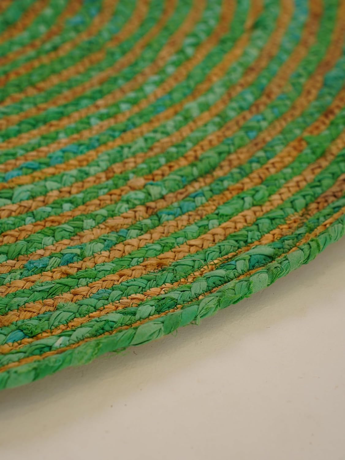Handwoven green and tan braided rug, made from natural materials, adding eco-friendly charm to your decor.