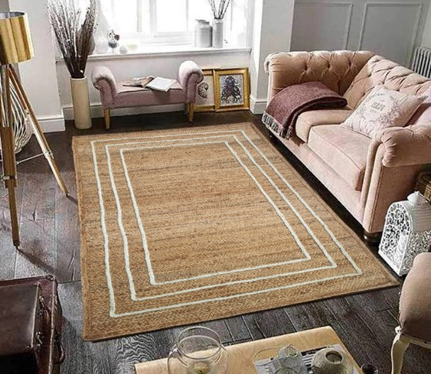 Living room with a beige area rug featuring a white border, pink sofa, and wooden coffee table.