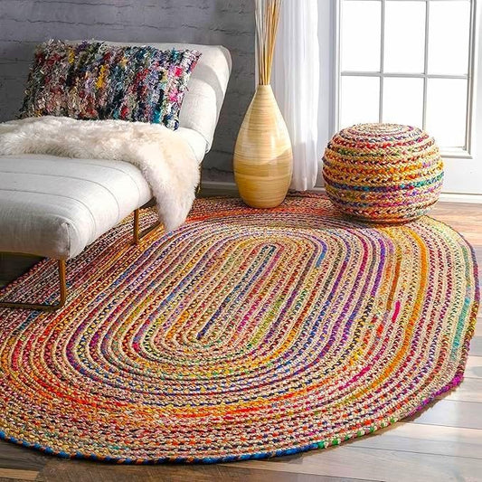 Multicolored braided rug in a living room setting with a white ottoman and decorative pillow.