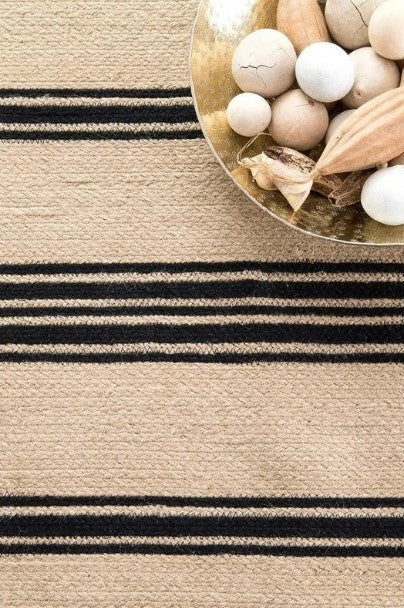 Beige and brown striped rug with decorative items on a gold tray