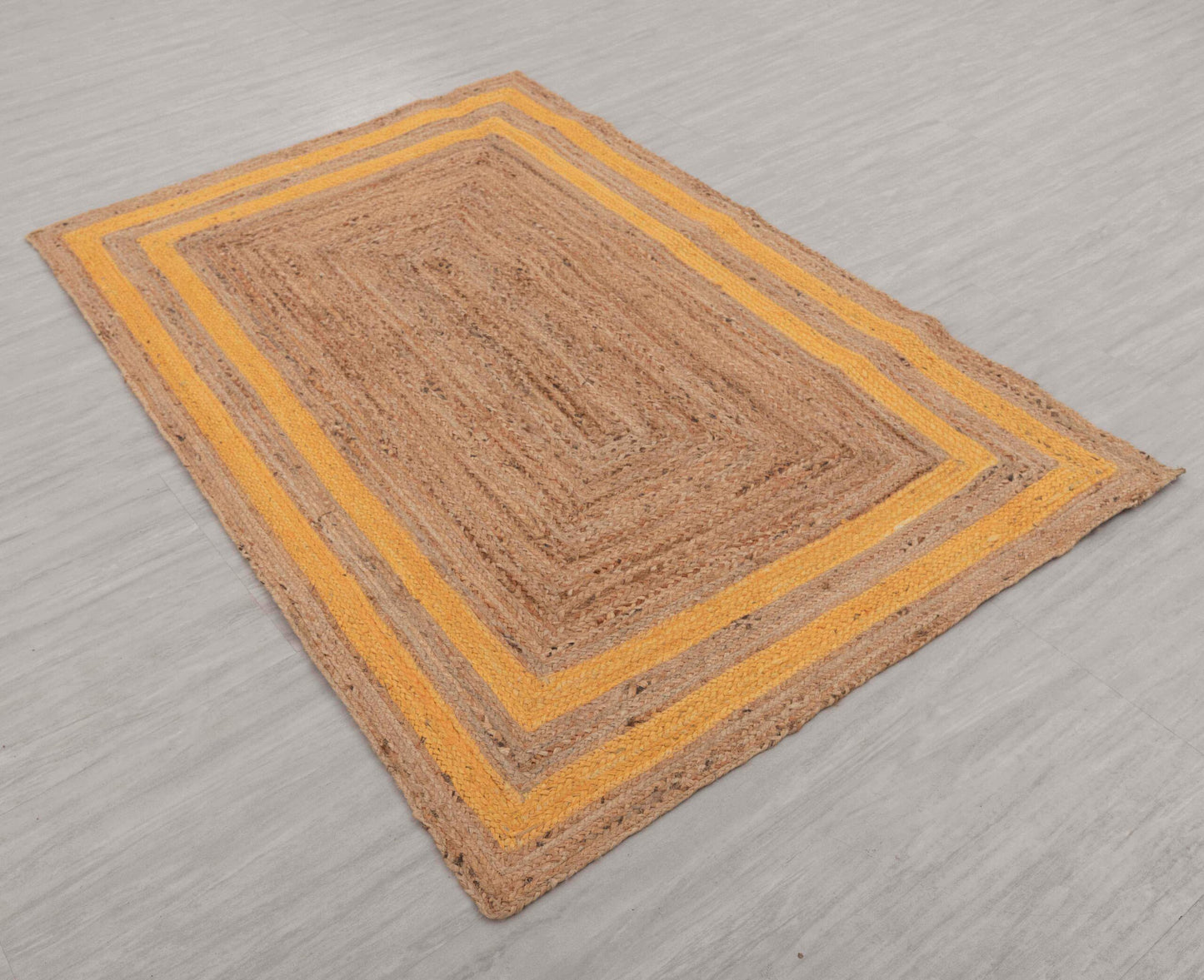 Rectangular jute rug with a yellow border on a gray floor.