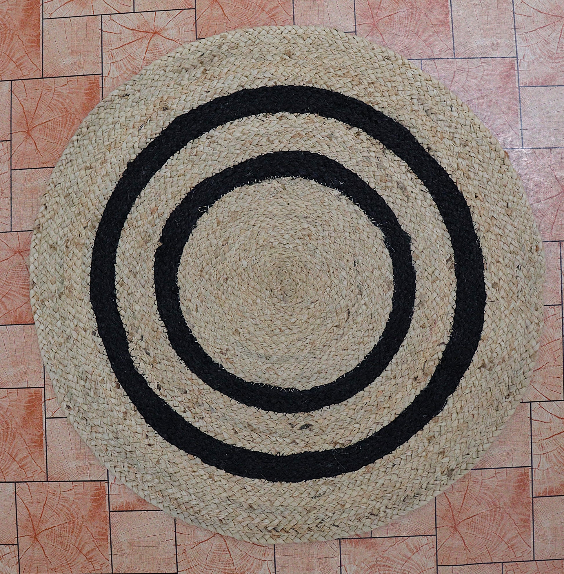 Round woven mat with concentric black circles on a tiled floor