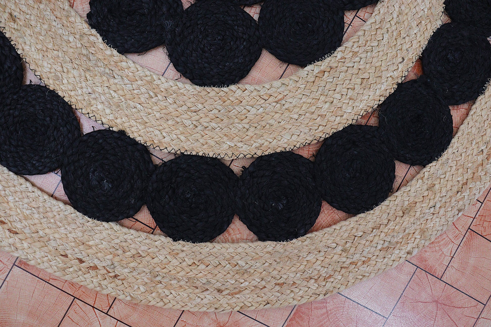 Round woven mat with black circular patterns on a tiled floor