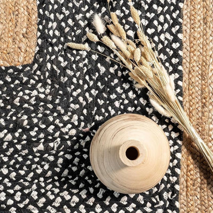 Black and white patterned fabric with a wooden spool and dried plants on top