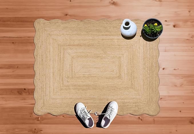 Beige woven mat on a wooden floor with a pair of white sneakers, a vase, and a plant.